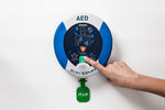 AEDの電源ボタンを手で押しています